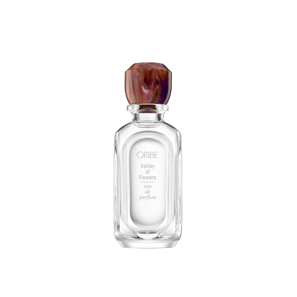 Elongated oval shaped glass bottle with a sculptural, one-of-a-kind resin cap (marbled purple and gold) with whose colour echoes the scent within.